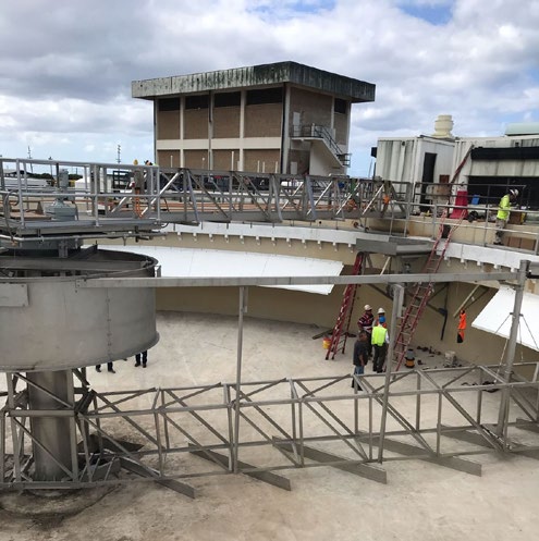A clarifier mechanism and walkway under construction at a Hawaii wastewater plant during startup, with a commissioning crew onsite